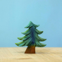 Bumbu Small Wooden Handmade Fir Tree in various shades of green, and a brown tree trunk displayed on a wooden table with a blue background