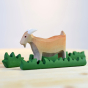 Bumbu handmade wooden billy goat toy stood on a light wooden work top next to some Bumbu wooden grass blocks