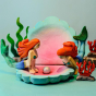 Two Bumbu wooden Mermaid toys posed on the Bumbu Shell With Pearl, surrounded by wooden toy seaweed and coral.