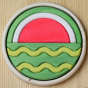 A round wooden puzzle depicting a watermelon in two halves. Different wooden shapes fit together to create the final puzzle. One half of the puzzle shows the inside of a watermelon whilst the other half shows the outside of a watermelon.