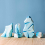 Bumbu handmade wooden icy rock toys lined up on a wooden worktop in front of a blue background