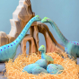 A baby brontosaurus pictured in a nest in front of wooden speckled eggs with big brontosaurus in the background 