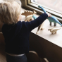 A child playing with the Bumbu Brontosaurus toys and natural dino toys on a window sill  