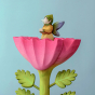 The Large Pink Flower by Bumbu is an impressive wooden flower with four leaves and a rich pink bloom, it stands on a green wooden base, and a Bumbu Elf is stood inside the flower, with a blue background. 