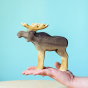 Bumbu Wooden Male Moose figure in persons hand pictured on a blue background
