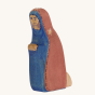 Bumbu Handmade Wooden Mary Figure kneeling down, on a cream background. Mary wears a royal blue and red dress with a small star detail.