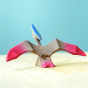 Bumbu Wooden Pteranodon Dinosaur. The toy sits on a wooden surface against a blue background.