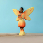 Bumbu Wooden Sunflower Fairy. A bright and cheerful wooden Sunflower Fairy has their arms outstretched in front of them. The sunflower Fairy has painted black hair, brown skin, yellow and orange wings with small orange spots, a yellow and orange dress wit