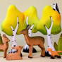 Bumbu Wooden Deer stand and lie infront of  Bumbu Wooden Birch Trees. A playful Bumbu fox is stood close by and a Miniature Wood Pecker is sitting in the tree tops