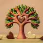 The Bumbu Wooden Heart Tree with a light brown Bumbu wooden heart sitting in the heart cut out center, surrounded by white and brown Bumbu hearts, on a warm beige background