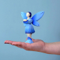 Bumbu Wooden Water Fairy Figure. The Water Fairy is coloured with hues of blue and silver on the wings, dress and boots, with inky blue hair, light blue eyes and pink lips. The Water Fairy is stood on a persons palm  with a blue background