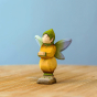 Bumbu Wooden Winged Elf. A whimsical and playful hand painted and hand crafted wooden elf with a painted green hat, blue and green wings, yellow and green outfit and light shoe details, stood on a light wooden table and a light blue background