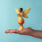 Bumbu Wooden Sunflower Fairy. A bright and cheerful wooden Sunflower Fairy is holding a yellow flower in their hands. The sunflower Fairy has painted black hair, brown skin, yellow and orange wings with small orange spots, a yellow and orange dress with g