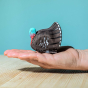 The Bumbu Turkey is a magnificent eco-friendly wooden male turkey toy, hand carved and painted with a black body with black and white wing feather details and fan tail, and a striking turquoise and red head. Adult hand for scale. 