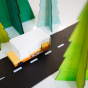 Close up of the Candylab childrens collectable campervan toy on a black rubber road next to some toy trees