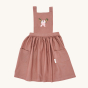Avery Row Kid's Pinafore Apron - Love Birds. A beautiful, dusky pink pinafore apron with two delicately embroidered pink love birds on the chest panel. Loosely pleated with two pockets on either side of the pinafore and the Avery Row label on the pocket.
