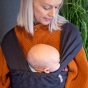 Close up of woman stood wearing the close caboo lite baby carrier in the nightfall colour