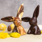 Cocoa Loco fairtrade dark chocolate and marbled easter rabbit on a beige worktop next to some mini easter eggs and daffodils