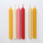 Six beeswax candles showing the different colours in the Grimm's range. white background. White background.