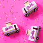 Picture of three pink cupcake vans on a bright pink background, along with colourful sprinkles.
