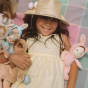 A child happily holding the Olli Ella Dinky Dinkum Doll Fluffles collection
