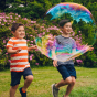 2 boys running after a giant Dr Zigs bubble in front of a pink flower bush