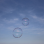 Close up of two Dr Zigs giant eco-friendly bubbles floating in a blue sky
