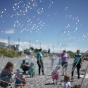 A close-up of the Dr Zigs multi-loop wand in action at the beach creating hundreds of bubbles filling the blue sky