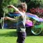 Boy holding up the Dr Zigs giant wooden bubble wand, with a long bubble trailing behind