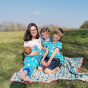 Woman and three children sat on a blanket on some grass wearing the DUNS Sweden organic cotton clothing in the blue puffin print