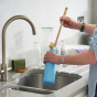 Person using a Ecoliving Wooden Bottle Brush to wash a blue reusable bottle in a kitchen sink 