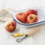 Ecoliving wooden apple corer on a kitchen worktop next to a cored apple and a bowl full of red apples