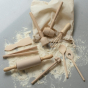 Evolving wooden mini kitchen utensil set with its natural cotton bag and flour spilt, on a grey background