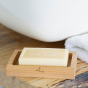 Close up of the Ecoliving natural plastic-free wooden soap dish on a wooden worktop next to a white towel