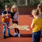 Children engaging and having fun using the marble track side of the Erzi balancing board. Each person is holding the wooden handles attached with red rope to the board, moving the metal balls along the track