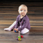 Toddler sat on a wooden floor playing with the Erzi eco-friendly rainbow screw turning learning game 