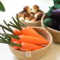 Bunch of Erzi Carrot Wooden Play Food in a Respiin bowl next to a bowl of wooden toy mushrooms and aubergines.