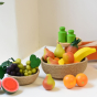 A fruit bowl filled with Erzi wooden play food with toy kitchen scales in the background. 