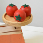 Three Erzi Tomato Wooden Play Food on a toy kitchen scales