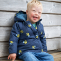 A child sits outdoors wearing the detachable jacket from the Frugi Waterproof All-In-One Suit - Buzzy Bee.