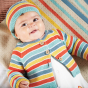 A baby wears the Frugi Bright As A Button Cardigan - Rainbow Stripe.