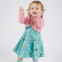 A young girl wears the Frugi Amy Bolero Cardigan - Pink Marl on a plain background.