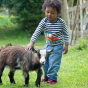 A child wears the Frugi Bobby Applique Top - Indigo Stripe / Tractor in an outdoor setting.