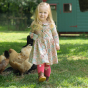 A child wears the Frugi Marta Dress - Floral Fun in an outdoor setting.