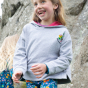 A child plays outdoors wearing the Frugi Switch Lissie Hoodie - Grey Marl / Wild And Wonderful.