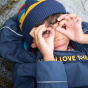 A young child plays outdoors wearing the Frugi Rambler 3 in 1 Coat - Indigo.