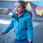 A young child wears the Frugi Rambler 3 in 1 Coat - Tor Blue in an outdoor setting.