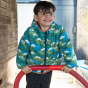 A young child wears the Frugi Reversible Toasty Trail Jacket - Birds of Prey / Indigo in an outdoor setting.