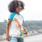 A child happily collecting pebbles and shells at the beach, wearing the Frugi Children's Organic Cotton Robbie Raglan T-Shirt - Squid. A soft 100% organic cotton t-shirt with a white body, contrasting blue raglan sleeves, and features a playful squid shoo