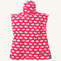The back of the Frugi Children's Organic Cotton Havana Hooded Towel - Raspberry Whales. A hot pink hooded towel with white while horizontal whale print. The inside of the towel is white with hot pink whale print, with blue piping. On a cream background